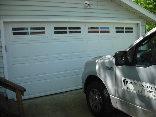 Picture of garage door with Doors Unlimited truck off to the side.
